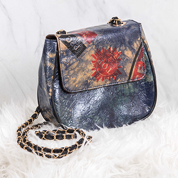 A dark blue HeySTARTIC handbag with markings from a recycled cement bag on the flap, and a fabric and metal shoulder strap