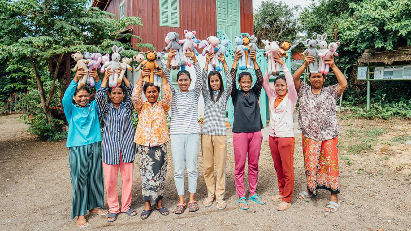 Group of women knitters each holding knitted stuffed animal dolls