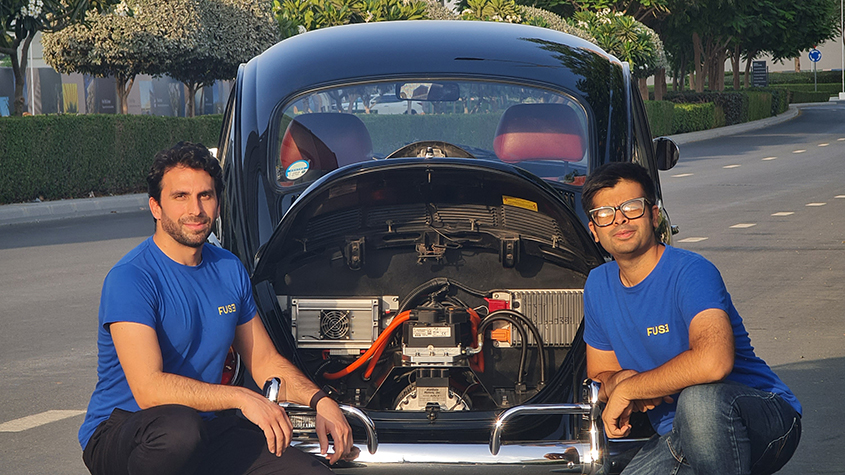 The FUSE team posing in front of the EV electric system of a classic Beetle car