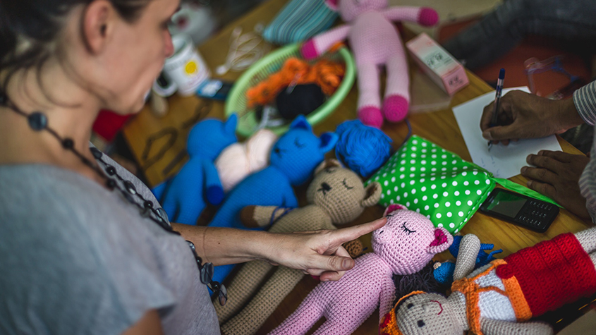Monica Nowaczyk looking down at several knitted animal dolls of different colors