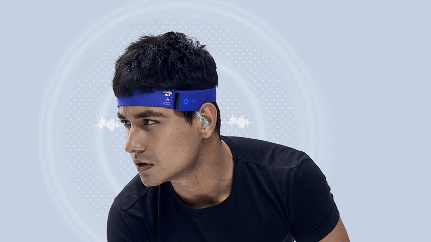 Photo d’un homme portant des écouteurs intelligents à bandeau bleu pendant qu’il joue au basket-ball.