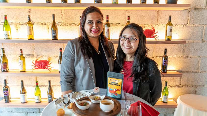 Shiok Meats founders, Dr. Sandhya Sriram, and Dr. Ka Yi Ling standing in front of a small table with samples of their products during a tasting event