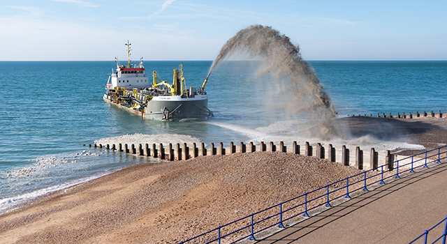 Hopper Dredger Spraying Shingle Back Onto The Beach In Eastbourne.