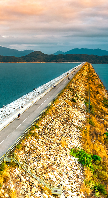 Aerial drone view of motorway road and cycling path on polder dam, cars traffic from above