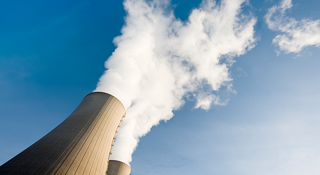 Tilt shot of Two steaming cooling towers against blue sky. Exposure with extreme wide-angle lens with tilt perspective.