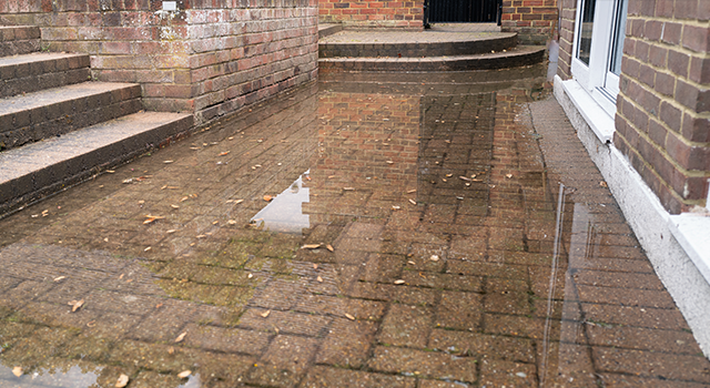 Brick patio area flooded after heavy rain due to a blocked soakaway, or block rain water drain