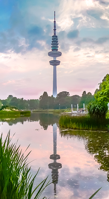 Beautiful view of flower garden in Planten um Blomen park with famous Heinrich-Hertz-Turm radio telecommunication tower in the background at dusk, Hamburg, Germany
