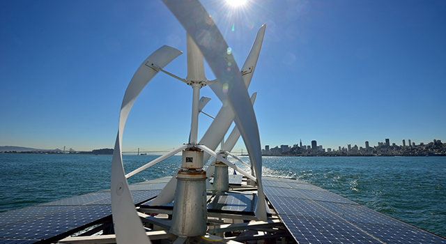 Solar panels and wind turbine on a boat in San Francisco Bay with city view behind. San Francisco, California