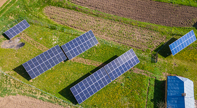 Aerial view of blue photovoltaic solar panels mounted on backyard ground for producing clean ecological electricity. Production of renewable energy concept.