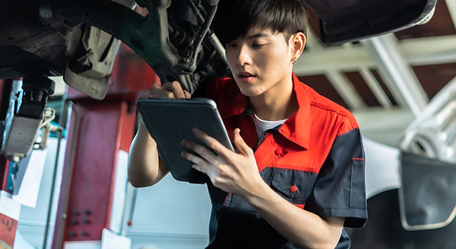 Auto service, repair, maintenance concept. Mechanic checks the car at the service station.Vehicle service maintenance asian men checking under car in garage.
