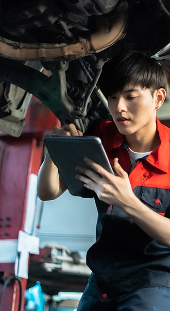 Auto service, repair, maintenance concept. Mechanic checks the car at the service station.Vehicle service maintenance asian men checking under car in garage.
