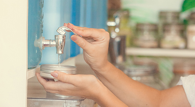 Young woman filling natural biodegradable household chemical product from container dispenser in zero waste plastic free store. Dispensers for detergents, shampoo, soap, conditioner.