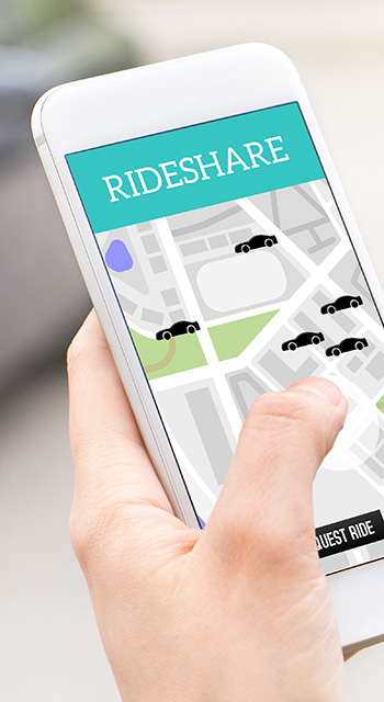 Ride share taxi service on smartphone screen. Online rideshare app and carpool mobile application. Woman holding phone with a car in the background. Person ordering ride with cellphone.