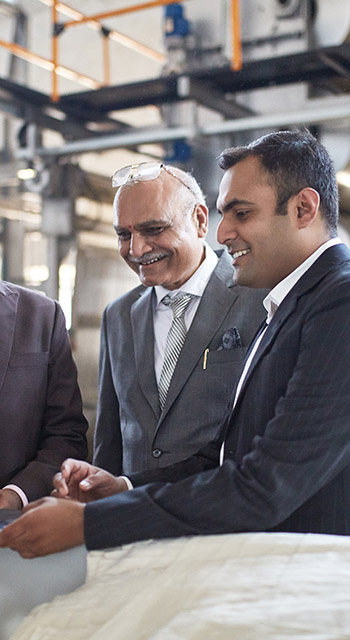 Indian CEO and senior managers meet on the factory floor to examine manufacturing methods and ensure quality control.