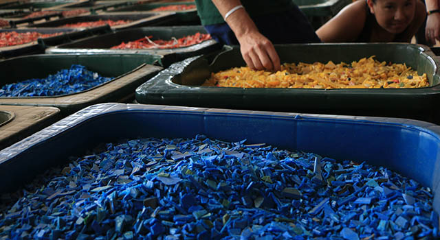 Tiny bits of recycled plastic in a bins in trash management facility in Ghana. They are colorful chips in giant trash bins, in a recycling center.