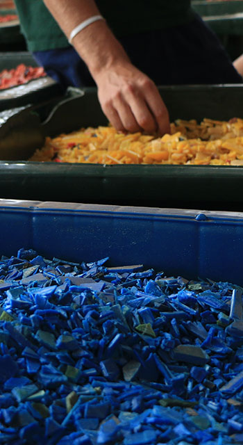 Tiny bits of recycled plastic in a bins in trash management facility in Ghana. They are colorful chips in giant trash bins, in a recycling center.
