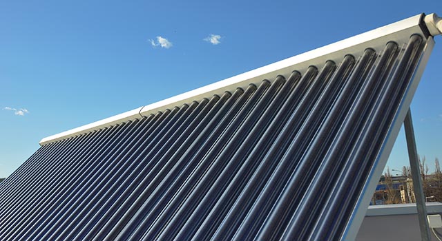 Energy efficiency and energy saving concept. Closeup of vacuum solar water heating system on the house metal roof.