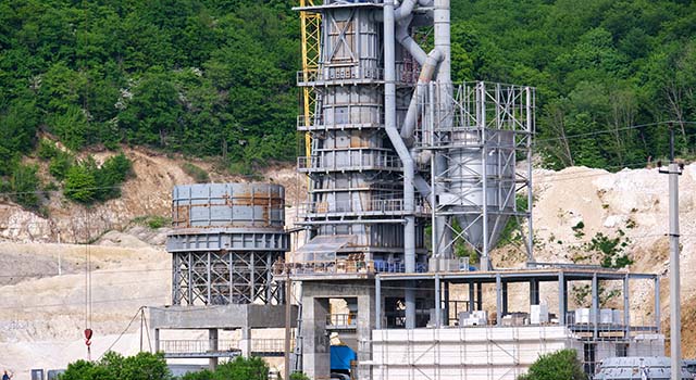 Cement plant with high metal factory structure at industrial production area. Manufacture and global industry concept.