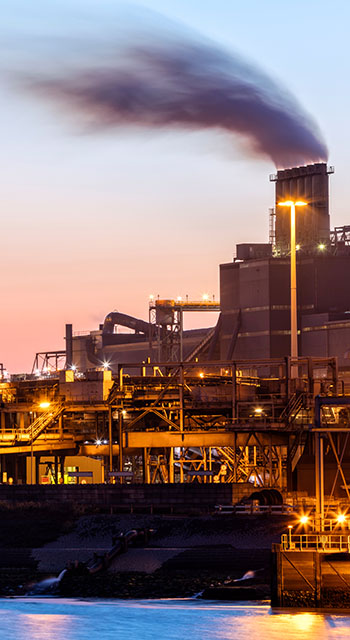 A large steelworks on the river illuminated at night in industrial district near Amsterdam, Netherlands, Benelux, Europe. Smoking chimneys, tanks and other installations are visible. Numerous colorful lights of a steel plant are reflected in the river. Long exposure with tripod, 50 megapixel image taken with the new Canon EOS 5Ds.