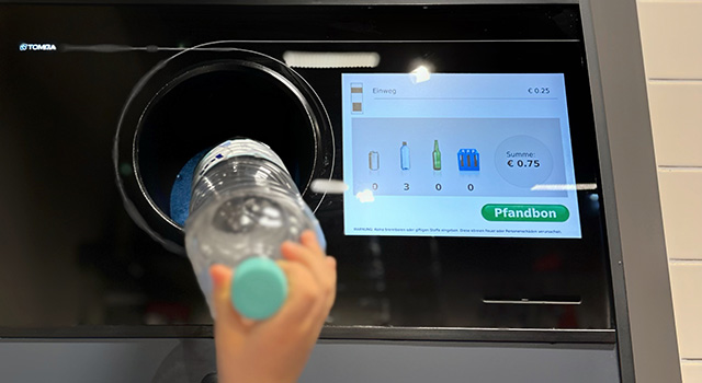 Little boy putting plastic bottles to the automatic recycling machine that is able to dispense refunds