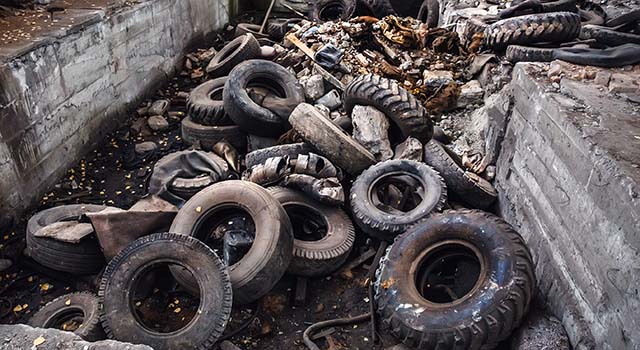 Heap of old car junk tires, used truck rubbish wheels, industrial garbage in abandoned factory, toned