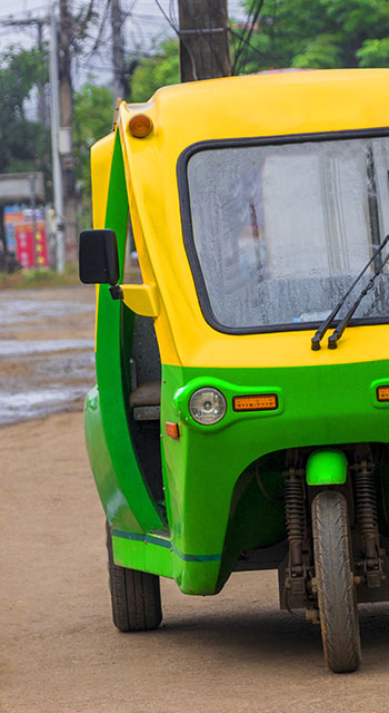 Green and yellow eco-friendly electronic tuk tuk vehicle car rickshaw in Luang Prabang Laos in Asia.