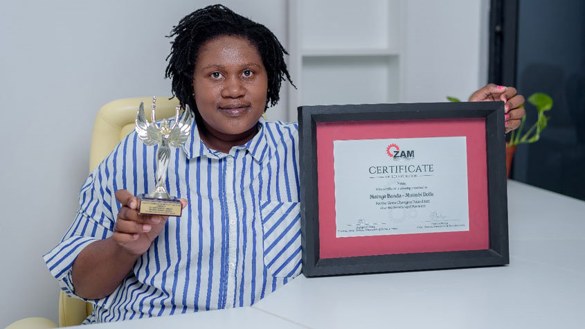 Photo ofMaingaila Moono holding the Game Changers Award trophy and certificate